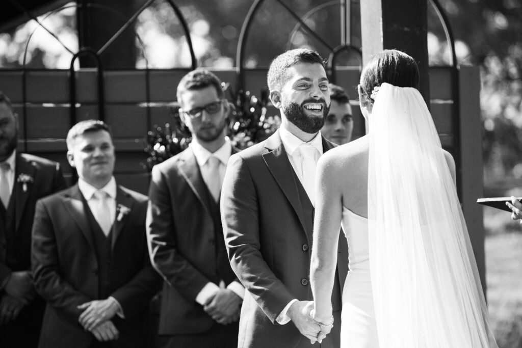 A groom smiling at a bride during their wedding ceremony