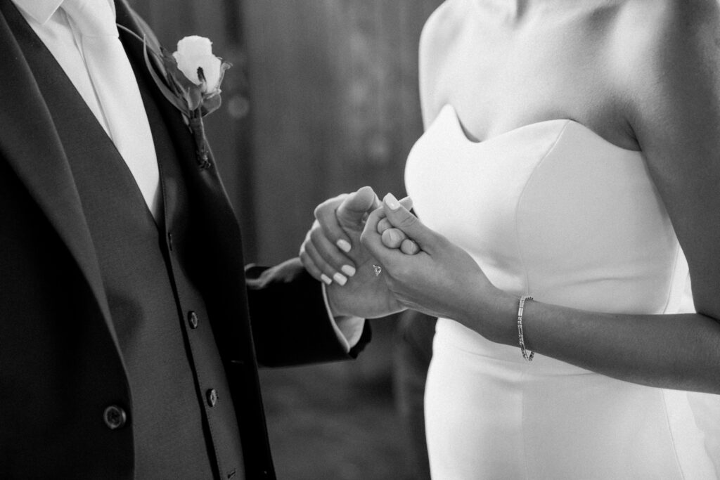 Close up of a groom and bride holding hands.