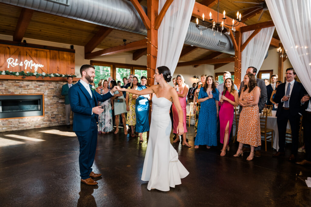 A bride and groom dancing as wedding guests watch