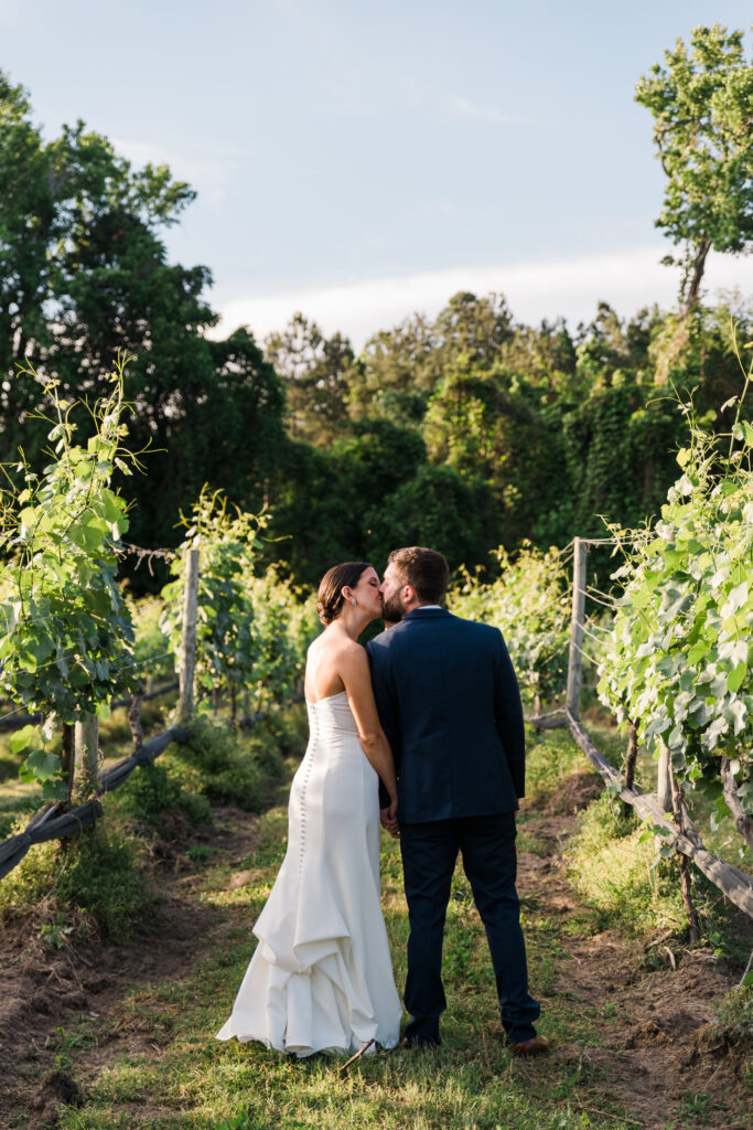 A bride and groom kissing in a vineyard