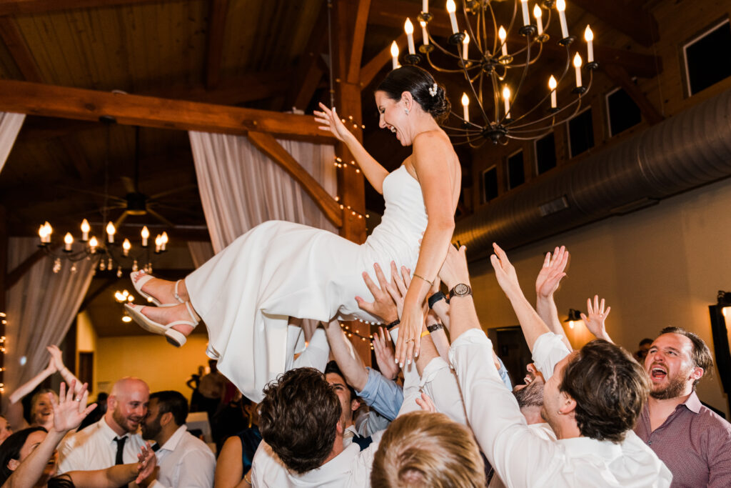 A bride being lifted up by guests during a wedding reception