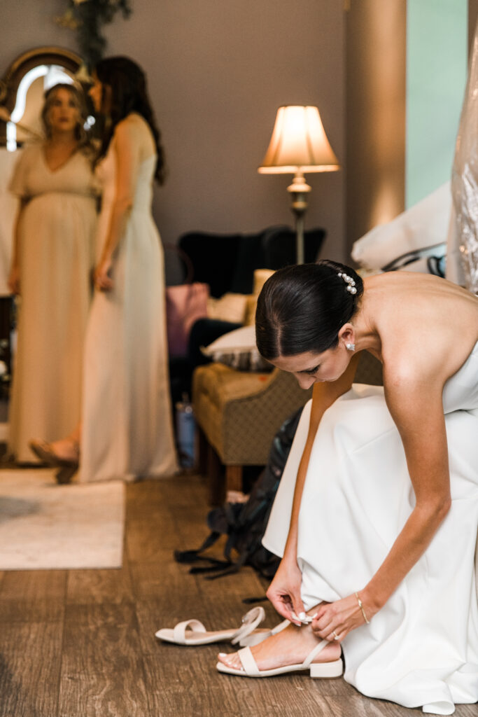 A bride bending down and putting on her shoe.