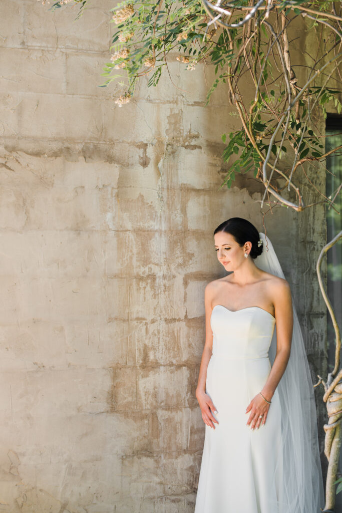 A bride in her wedding dress standing next to a wall