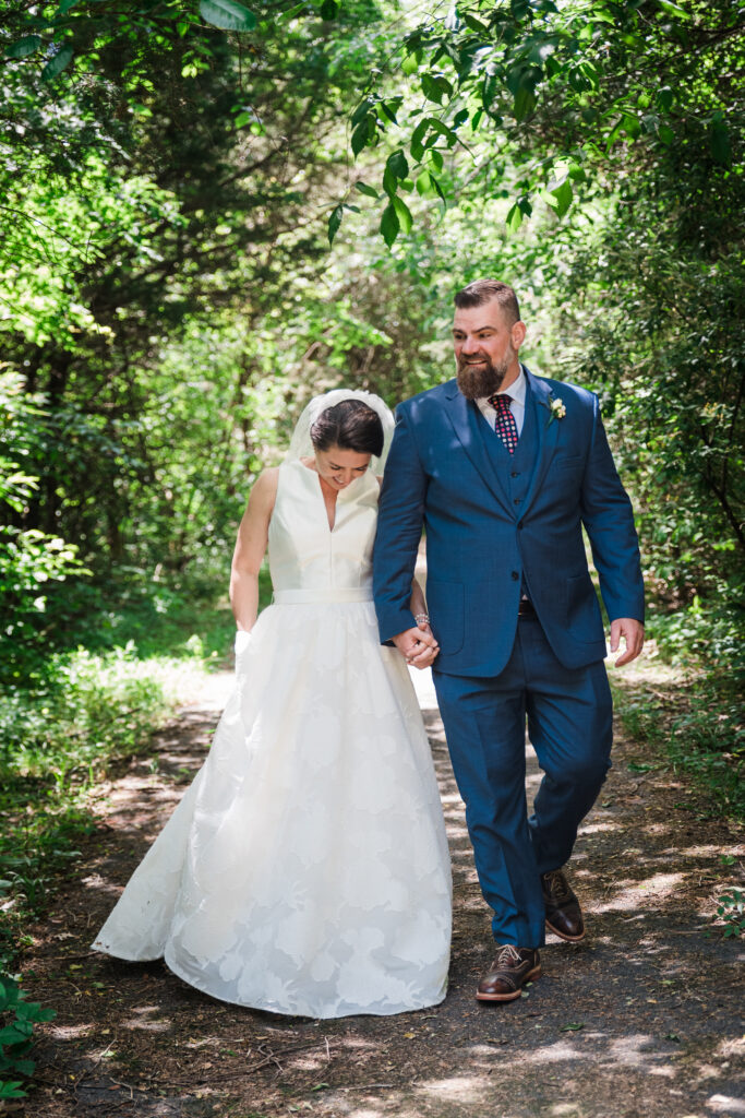 Bride and groom walking in the woods holding hands