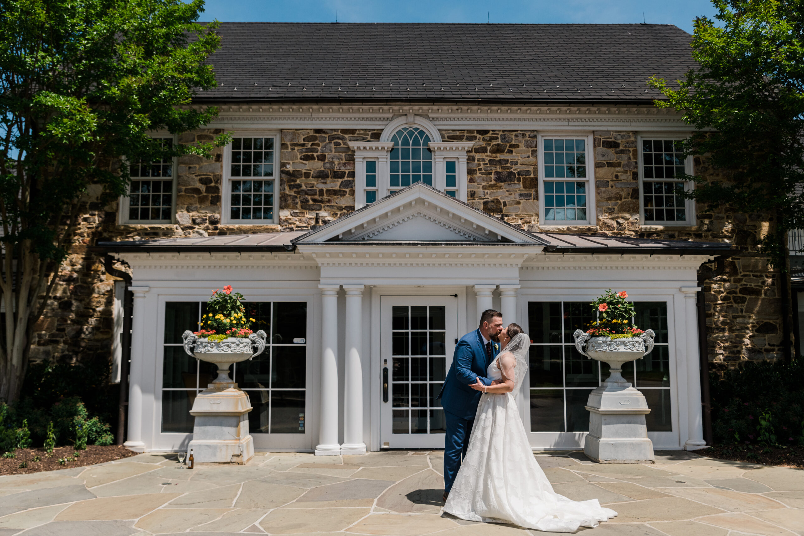 A bride and groom standing in front of a building kissing