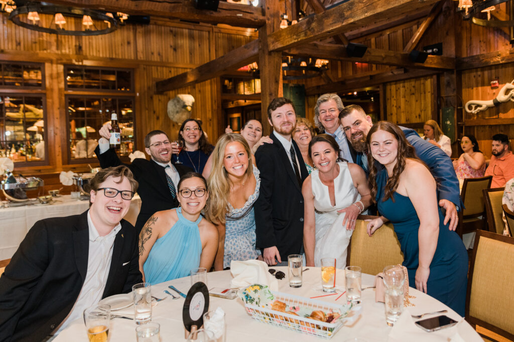 A group shot of men and women around a table, smiling at the camera