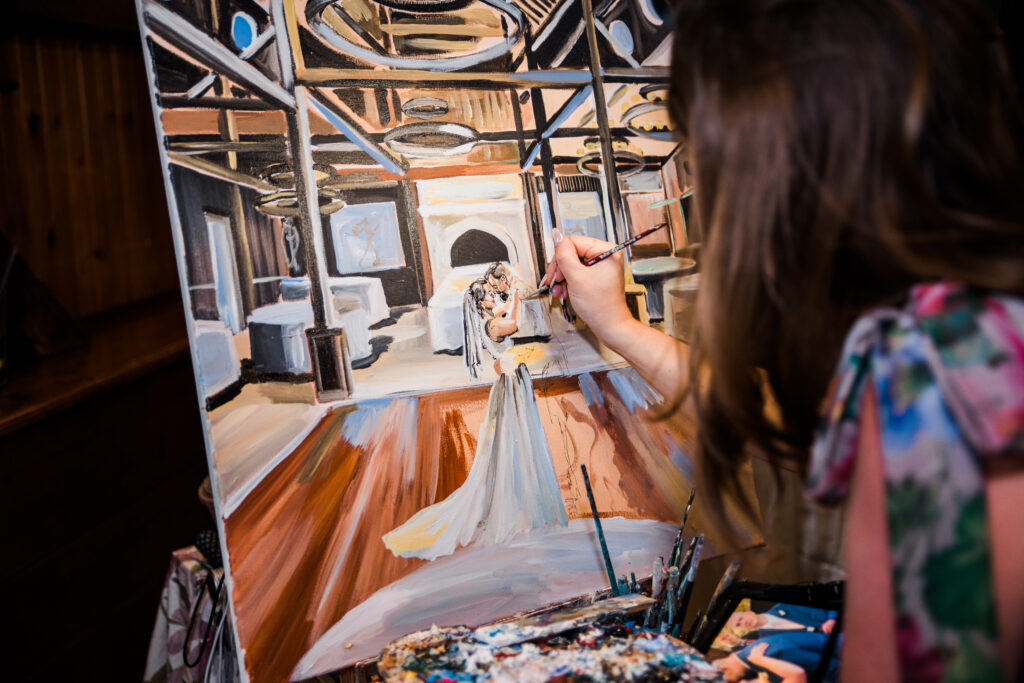 A woman painting a picture of a bride and groom dancing