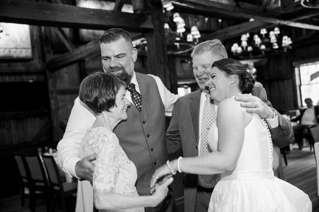 Black and whit picture of a bride and groom holding hands with an older couple