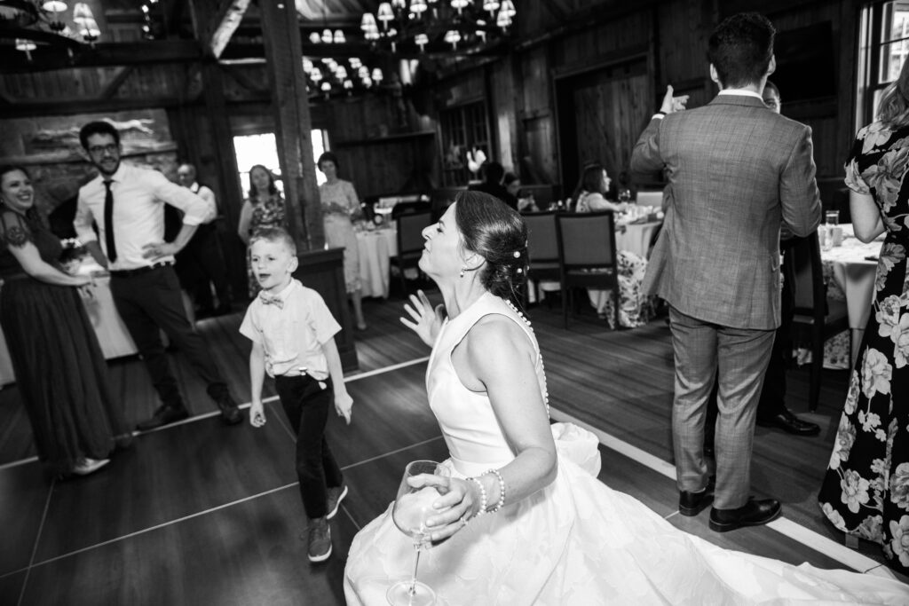 A black and white picture of a bride dancing with a little boy