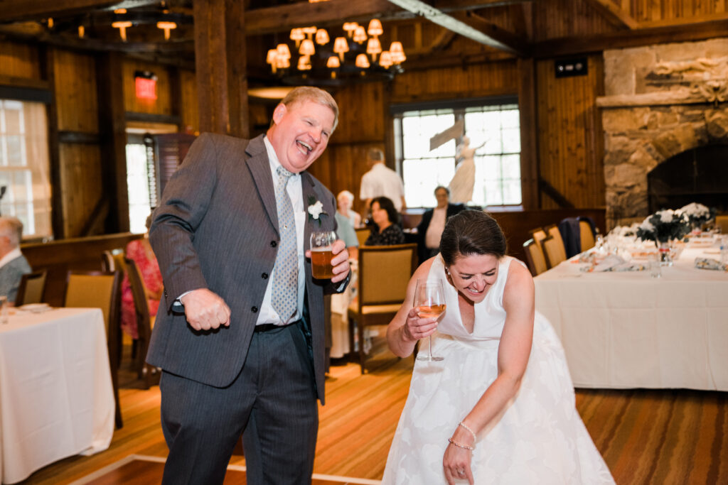 A bride laughing with a man at a wedding reception