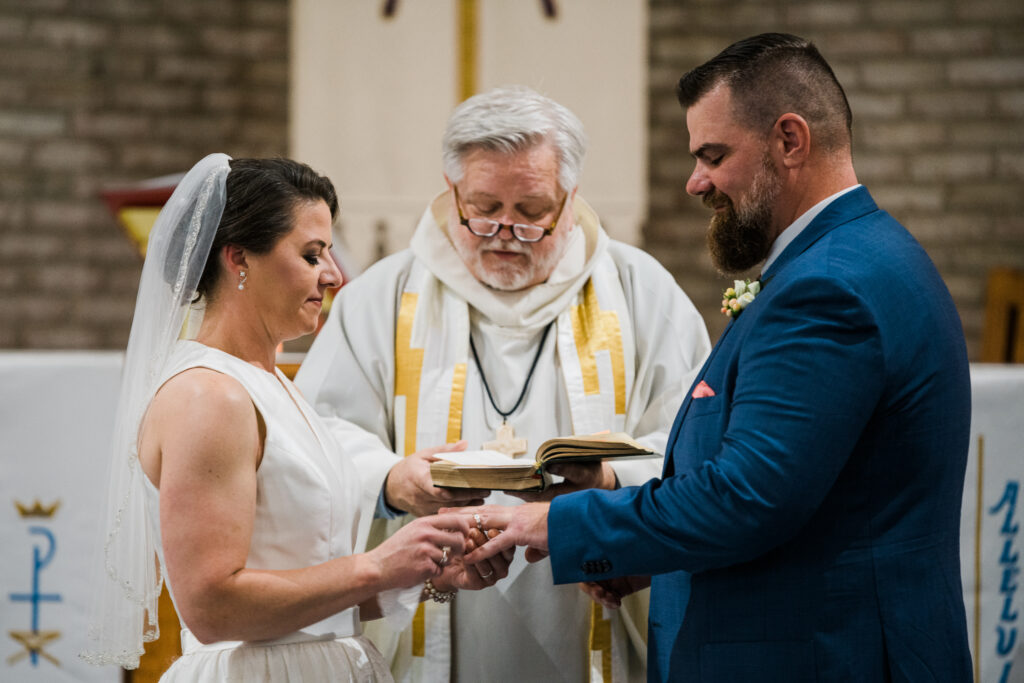 A bride and groom holding hands in front of a priest